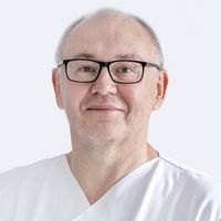 Porträt eines älteren Mannes mit Brille und weißem Hemd vor hellem Hintergrund